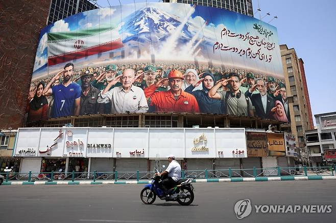 22일(현지시간) "우리는 모두 이란의 군인이다"라 쓰인 광고판을 지나는 테헤란 시민 [EPA 연합뉴스]