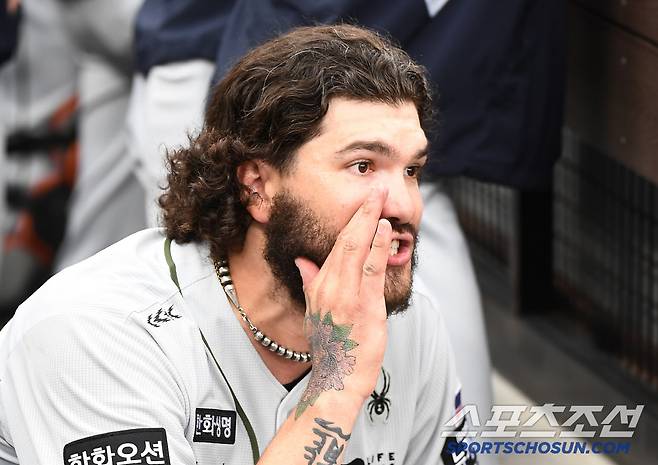 더그아웃에 들어온 폰세가 출입구 쪽에 쪼그려 앉아 1루주자 최주환을 부르고 있다.