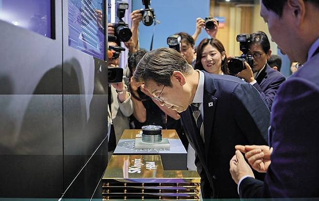 이재명 대통령이 20일 울산전시컨벤션센터에 마련된 SK하이닉스 부스에서 확대경을 통해 이 회사의 고대역폭 메모리(HBM) 제품을 보고 있다. AI 데이터센터의 두뇌 역할을 하는 반도체는 엔비디아가 만드는데, 그 핵심 부품 중 하나가 HBM이다. /대통령실