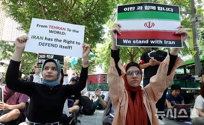 [서울=뉴시스] 추상철 기자 = 트럼프 미국 대통령이 이란의 주요 핵 시설을 파괴했다고 밝힌 22일 오후 서울 종로구 교보빌딩 인근에서 열린 노동자연대의 '전쟁 중단 및 이스라엘 공격 규탄집회'에서 이란인 집회 참가자가 피켓을 들고 전쟁 중단을 촉구하고 있다. scchoo@newsis.com 2025.06.23.