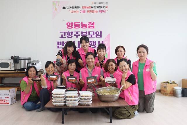 김혜진 충북 영동농협 고향주부모임 회장(앞줄 오른쪽 세번째)과 회원·영동농협 직원들이 정성껏 준비한 반찬을 들어보이며 지역사회를 위한 따뜻한 활동을 이어갈 것을 다짐하고 있다.