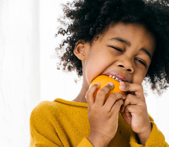 양손에 무언가를 잡고 입에 가져가 물고 있는 아이