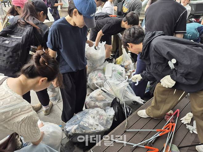 지난 21일 오전 서울 관악구 신림 일대에서 자발적으로 모인 시민들이 하수구를 청소하고 모은 쓰레기들을 종량제봉투에 정리하고 있다. (사진=정윤지 기자)