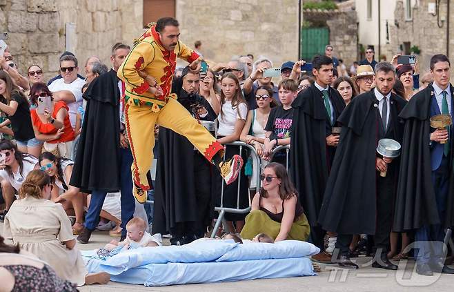 22일(현지시간) 스페인 부르고스 인근 카스트리요 드 무르시아 마을에서 열린 '엘 콜라초(El Colacho)'축제에서 악마를 상징하는 '콜라초'가 아기들을 뛰어넘고 있다.ⓒ AFP=뉴스1