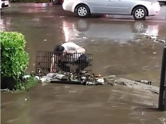 2022년 8월 갑자기 쏟아진 폭우로 서울 강남역 일대가 침수되자 한 남성이 맨손으로 빗물 배수구에서 쓰레기와 낙엽을 치워 물이 빠지게 하고 있다. /온라인 커뮤니티 제공