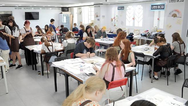 ‘2024 PNU 서머 스쿨’에 참가한 외국인 학생들이 한글 캘리그라피 수업을 통해 전통 부채를 만드는 체험을 하고 있다. 부산대 제공