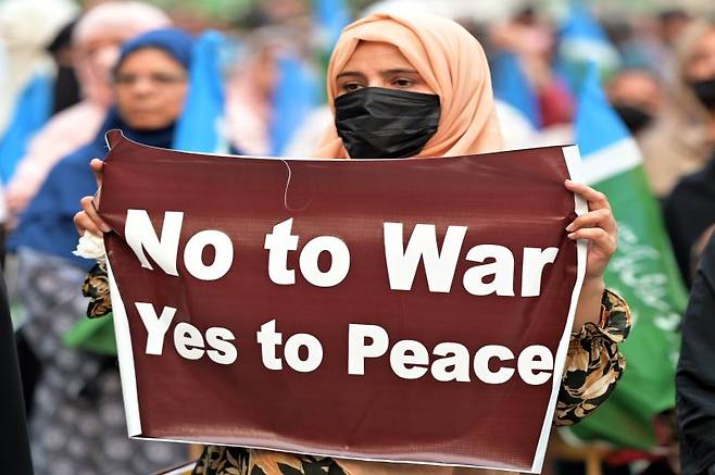 파키스탄 라호르에서 23일(현지시간) 시위대가 이란과 연대하는 한편 전쟁에 반대하고 평화를 추구한다는 구호가 담긴 팻말을 들고 시위하고 있다. 이란이 이날 카타르와 이라크 미군 기지를 공습했지만 사전 통보로 인명 피해가 나지 않으면서 국제 유가는 7% 넘게 폭락했다. EPA 연합