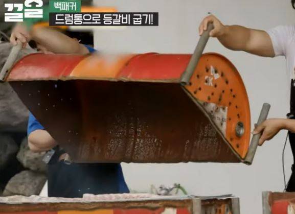 백종원 더본코리아 대표가 녹슨 엔진오일 드럼통을 돼지고기 요리 덮개로 사용하고 있다. [사진=유튜브 '백패커' 캡처]