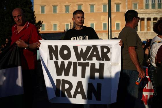 2025년 6월 23일 그리스 아테네에서 미국의 이란 핵시설 공격에 항의하는 시위 도중 한 시위자가 피켓을 들고 있다. 로이터=연합뉴스