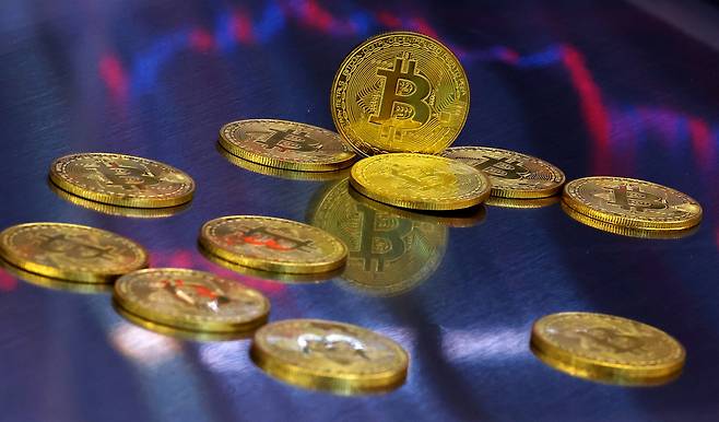 사진은 비트코인 모형이 놓인 바닥에 코인 시세 그래프가 비치는 모습. 연합뉴스