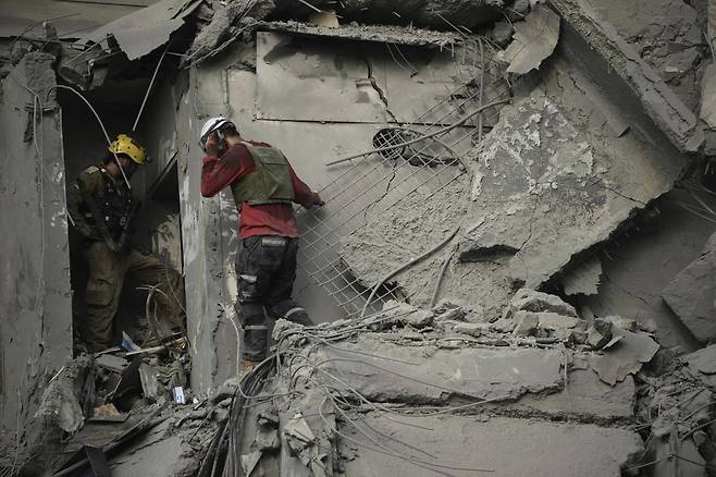 24일(현지 시간) 이스라엘 남부 베르셰바에서 이스라엘 구조대가 이란의 미사일 공격으로 파괴된 주거 건물 잔해를 수색하고 있다. AP뉴시스