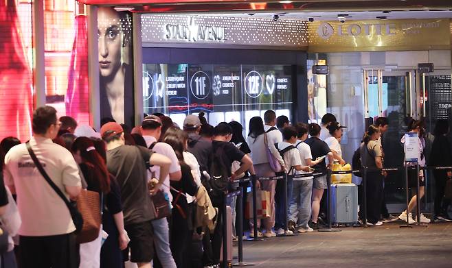 서울 시내 한 면세점 앞에서 관광객들이 입장을 위해 대기하고 있다. [연합]