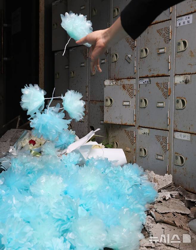 [화성=뉴시스] 김종택 기자 = 24일 오전 경기 화성시 전곡리 아리셀 참사 화재현장에서 열린 '아리셀 참사 1주기 현장 추모 위령제'에서 유가족들이 화재 건물 안으로 파란꽃을 던지고 있다. (공동취재) 2025.06.24. photo@newsis.com