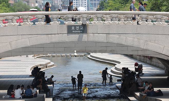 지난 6월 23일 서울 청계천을 찾은 시민과 관광객들이 모전교 아래 그늘에서 햇빛을 피하고 있다. 연합뉴스