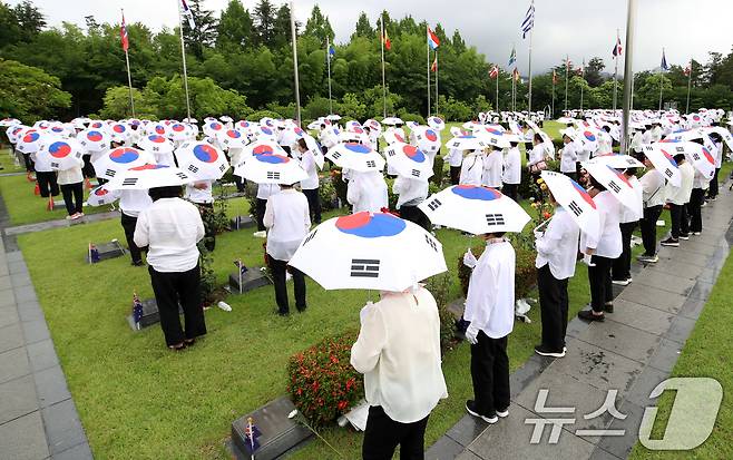 25일 오전 부산 남구 유엔기념공원에서 열린 제75주년 6·25전쟁 참전 유엔전몰용사 추모제에서 태극기 우산을 쓴 참석자들이 유엔군 전몰장병 묘역을 참배하고 있다. 2025.6.25/뉴스1 ⓒ News1 윤일지 기자