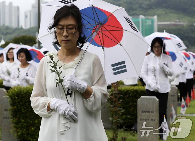 25일 오전 부산 남구 유엔기념공원에서 열린 제75주년 6·25전쟁 참전 유엔전몰용사 추모제에서 태극기 우산을 쓴 참석자들이 유엔군 전몰장병 묘역을 참배하고 있다. 2025.6.25/뉴스1 ⓒ News1 윤일지 기자