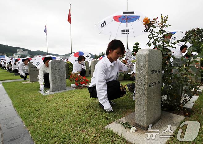 25일 오전 부산 남구 유엔기념공원에서 열린 제75주년 6·25전쟁 참전 유엔전몰용사 추모제에서 태극기 우산을 쓴 참석자들이 유엔군 전몰장병 묘역에 헌화하고 있다. 2025.6.25/뉴스1 ⓒ News1 윤일지 기자