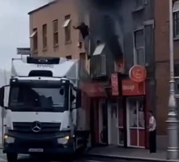 지난 23일(현지시간) 아일랜드 더블린 그랜비 로우의 한 3층 건물에 화재가 발생한 가운데, 한 시민이 건물에서 트럭 위로 뛰어내리고 있다. [데일리메일 캡처]