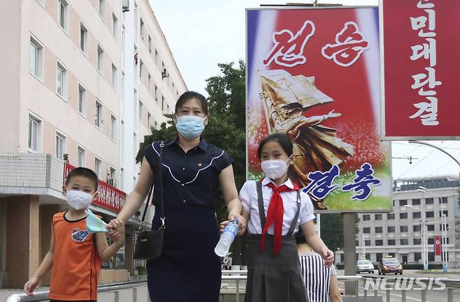 [평양=AP/뉴시스] 6·25 한국전쟁 정전 69주년인 2022년 7월 27일 북한 평양의 승리 거리에서 한 여성이 아이들과 함께 '전승 경축'이라는 포스터 앞을 지나고 있다. 북한은 6·25 한국전쟁 정전 체결을 미군에 승리했다고 주장하며 '조국 해방전쟁 승리의 날'로 기념한다. 2025.06.25.