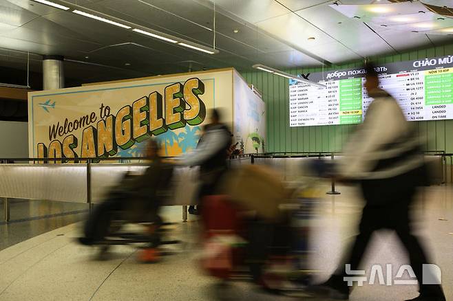 [로스앤젤레스=AP/뉴시스]8일(현지시각) 미 로스앤젤레스 국제공항에 도착한 여행객들이 짐을 실은 카트를 밀며 이동하고 있다. 도널드 트럼프 대통령의 이민법 시행 캠페인을 둘러싸고 긴장이 고조되는 가운데 9일 아프리카와 중동을 중심으로 한 12개국 시민들의 미국 입국 금지가 발효됐다. 2025.06.09.