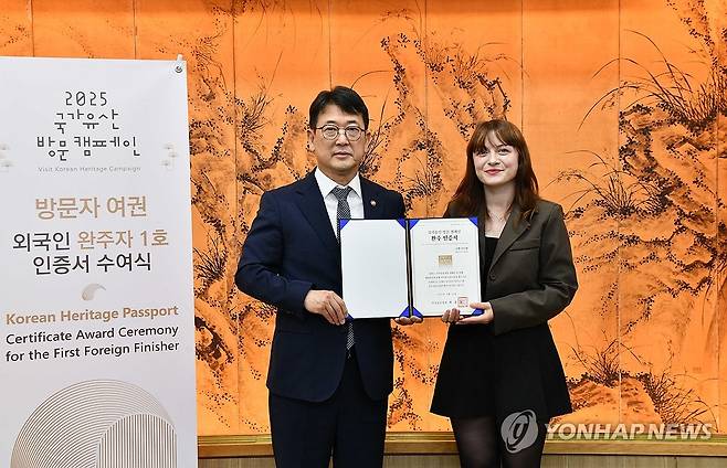 방문자 여권 외국인 완주자 1호 인증서 수여식 (서울=연합뉴스) 최응천 국가유산청장이 지난 10일 서울 종로구 국립고궁박물관에서 국가유산을 방문한 후 인증하는 '국가유산 방문자 여권 투어' 프로그램을 외국인 최초로 완주한 튀르키예 국적의 쿠벳 아이셰(오른쪽)씨와 기념 촬영하고 있다. 2025.6.25 [국가유산청 제공. 재판매 및 DB 금지] photo@yna.co.kr