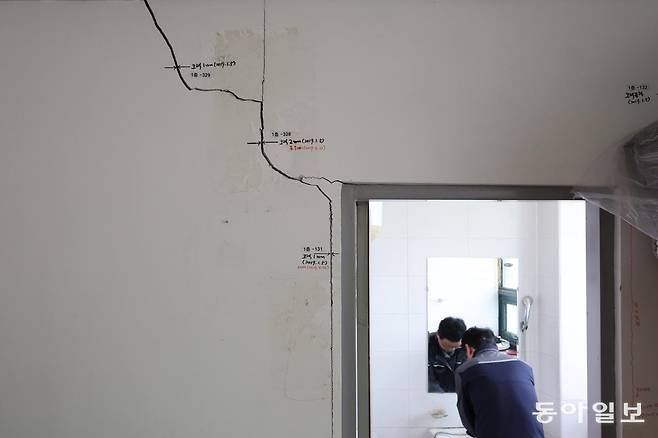 지난달 29일 충남 당진시 아산국가산업단지 부곡지구 내 녹조제거 장비 생산 공장에서 한 직원이 벽면 곳곳에 균열이 나있는 화장실을 이용하고 있다. 균열 옆으론 발견 시점과 발전 양상 등이 마카로 기록돼있다.  6년 전 한국전력 지하 굴착공사로 피해를 입은 이 공장은 건물안전진단에서 D등급(붕괴 위험이 있어 사용제한 여부를 결정해야 할 단계)을 받았지만 수 년째 복구가 이뤄지지 않고 있다. 히어로콘텐츠팀