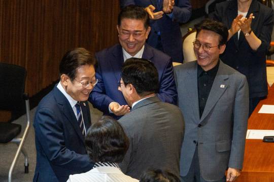 이재명 대통령이 26일 30조5000억원 규모 추가경정예산(추경)안 편성에 대한 시정연설을 하기 위해 국회 본회의장으로 들어서며 더불어민주당 김병기 원내대표, 당대표 후보인 박찬대 의원, 국무총리 후보자인 김민석 의원과 인사하고 있다.<국회사진기자단·연합뉴스>