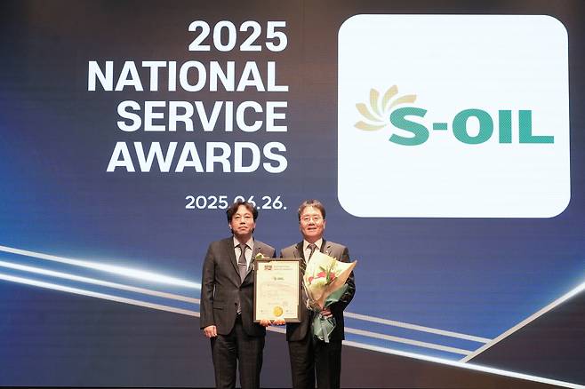 S-Oil Executive Vice President of Sales Strategy Lee Young-ho, right, takes a commemorative photo with Hur Jong-ho, head of the judging panel and a business professor at Seoul Women’s University, at the 2025 National Service Awards ceremony on June 26. [S-OIL]