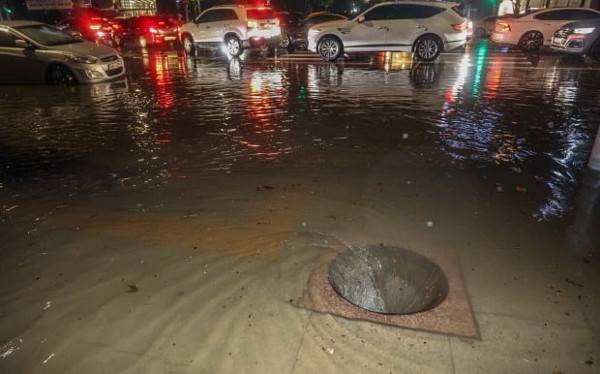 서울 강남구 한복판에 위치한 맨홀 뚜껑이 빗물에 의한 압력을 이기지 못하고 날아가자 뻥 뚫린 구멍 안으로 빗물이 소용돌이 치며 빨려 들어가고 있다. 연합뉴스