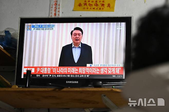 [수원=뉴시스] 김종택 기자 = 윤석열 대통령에 대한 2차 체포영장이 집행된 15일 경기도 수원시 못골시장에서 한 상인이 관련 뉴스를 시청하고 있다. 2025.01.15. jtk@newsis.com