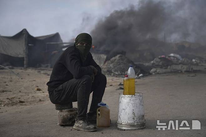 <font style="vertical-align: inherit;"><font style="vertical-align: inherit;">[가자시티=AP/뉴시스] 지난 22일(현지 시간) 가자지구 가자시티 남쪽 시로드에서 팔레스타인 청년이 플라스틱에서 추출한 연료를 판매하고 있다. 팔레스타인 청년들은 플라스틱 폐기물을 금속 드럼에 넣고 가열해 만든 연료를 병에 담아 판매하며, 이는 현지에서 발전기나 이동용 연료로 사용된다. 유독한 연기와 불길에 노출되는 고된 작업이지만, 이들에게는 가족의 생계를 이어가는 거의 유일한 수단이다. 2025.06.25.</font></font>