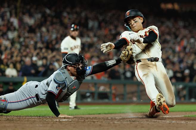 샌프란시스코 자이언츠 이정후가 26일(한국시각) 마이애미 말린스전에서 9회말 볼넷으로 출루한 뒤 패트릭 베일리의 좌전안타 때 2루에서 홈까지 파고들다 태그아웃당하고 있다. 3루 방향 파울지역에서 매트 윌리엄스 3루코치가 이를 지켜보고 있다. Imagn Images연합뉴스