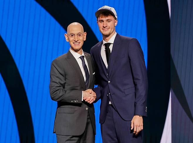 2025 미국프로농구(NBA) 신인 드래프트 전체 1순위로 댈러스 유니폼을 입게 된 쿠퍼 플래그(오른쪽)가 26일 드래프트가 열린 미국 뉴욕주 브루클린의 바클레이스센터에서 애덤 실버 NBA 총재와 악수하고 있다. 브루클린=AP 뉴시스