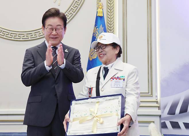이재명 대통령이 27일 청와대 영빈관에서 열린 ‘호국보훈의 달, 대통령의 초대’ 행사에서 특별초청 대상자인 6·25전쟁 참전유공자 이춘자 참전용사에게 광목이불 선물을 전달 후 박수치고 있다. (대통령실통신사진기자단) 2025.06.27.