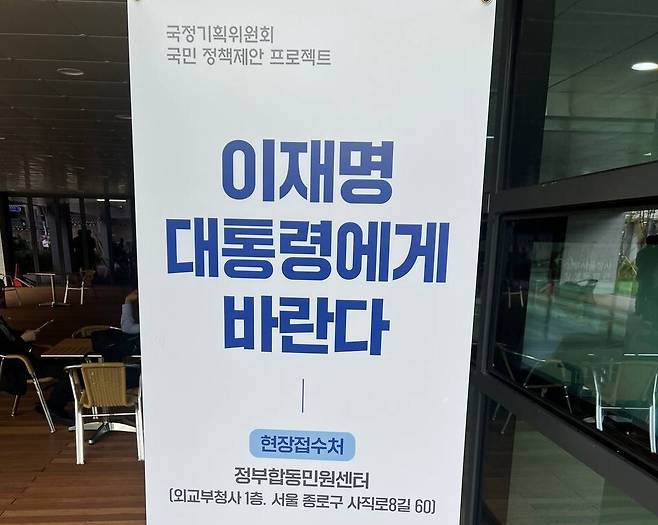 지난 24일 서울 종로구 국정기획위원회 출입구 옆에 온라인으로 국정기획위원회에 정책을 제안할 수 있는 ‘모두의 광장’ 누리집으로 연결되는 큐알코드가 그려진 입간판이 세워져 있다. 최현수 기자