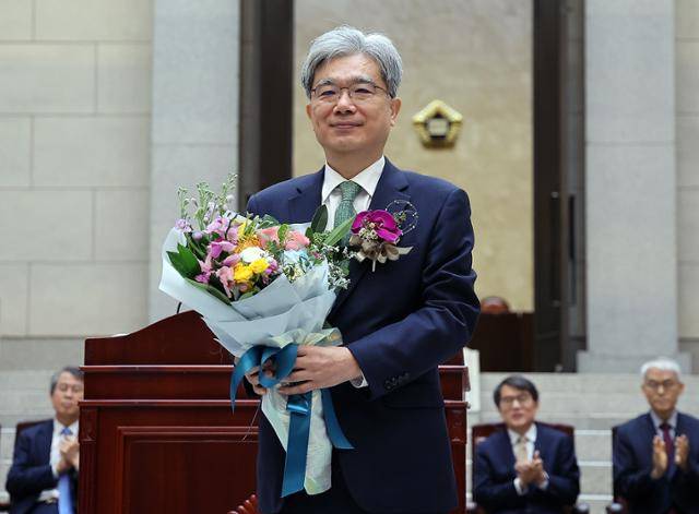 김상환 헌법재판소장 후보자가 지난해 12월 27일 서울 서초구 대법원에서 열린 퇴임식에서 꽃다발을 받은 뒤 기념 촬영을 하고 있다. 뉴스1