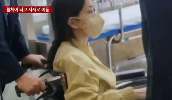 Kim Keon Hee, wife of former President Yoon Suk Yeol, is escorted out of Seoul Asan Medical Center in a wheelchair on June 27, 11 days after being hospitalized for treatment of depression and panic disorder, in this screen capture of a video from YTN. [SCREEN CAPTURE]
