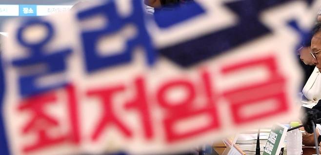 17일 세종시 정부세종청사에서 열린 최저임금위원회 5차 전원회의에서 한 근로자 위원이 쓴 머리띠 뒤로 노사 위원들이 진지한 표정을 짓고 있다. 뉴시스