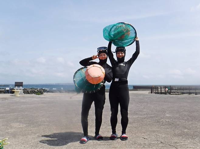 제주 하도어촌체험마을의 해녀물질체험에 참가한 관광객이 태왁과 망사리를 들고 기념사진을 찍고 있다    사진제공｜한국관광공사