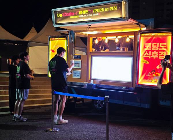 27일, 의성 해커톤 현장에 설치된 야간 푸드트럭에서 참가자들이 '코딩도 식후경'이라는 문구 아래 따뜻한 음식으로 에너지를 보충하고 있다. 김동현 기자 jhass80@kyongbuk.com