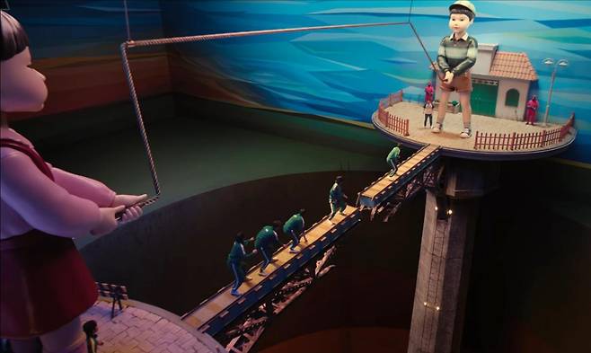 ‘오징어 게임’ 시즌3에 등장하는 게임 ‘줄넘기’의 한 장면(위 사진). 시즌1 ‘무궁화 꽃이 피었습니다’의 살인 기계였던 ‘영희’가 친구 ‘철수’와 함께 거대한 줄을 돌리고 있다. 넷플릭스 제공