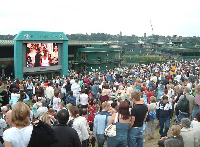 쇼 코트 입장권이 없는 관중들이 1번 코트 옆에 있는 대형 스크린을 통해 테니스 경기를 실시간으로 관람하는 모습. 이곳의 정식 명칭은 ‘아오랑이(Aorangi) 테라스’이나 ‘헨만 힐(hill, 언덕)’이란 애칭으로 주로 불린다. 이러한 애칭의 유래는 1990년대 후반 영국 팬들이 자국 선수인 팀 헨만의 경기를 보기 위해 이곳에 모여들면서 생겨났다. 운이 좋으면 이곳에서 이동 중인 유명 선수를 실제로 볼 수도 있다. 위키피디아