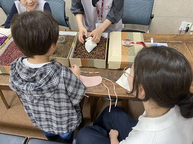 [서울=뉴시스] 소나무센터 '솔방울 힐링모임'에서 온열안대 만들기 체험을 하는 모습. 2025.06.27 (사진 제공=동대문구청) photo@newsis.com *재판매 및 DB 금지