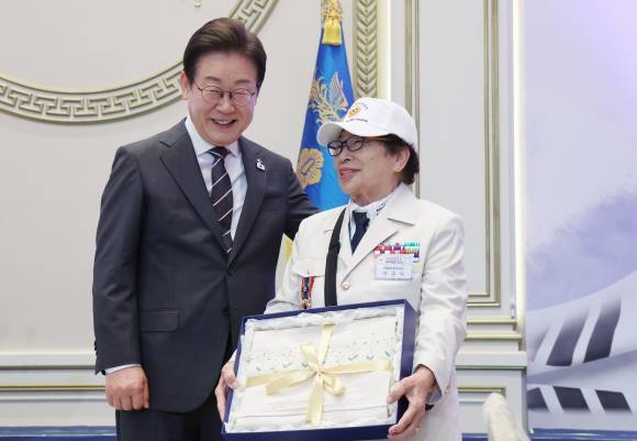 참전용사에게 선물 전달한 이재명 대통령 - 이재명 대통령이 27일 청와대 영빈관에서 열린 ‘호국보훈의 달, 대통령의 초대’ 행사에서 특별초청 대상자인 6·25전쟁 참전유공자 이춘자 참전용사에게 광목이불 선물을 전달 후 미소짓고 있다. 대통령실통신사진기자단 2025.06.27.