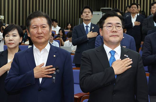 더불어민주당 당대표 후보인 정청래(왼쪽)·박찬대 의원이 지난 24일 서울 여의도 국회에서 열린 의원총회에서 국기에 경례하고 있다. [사진 출처 = 연합뉴스]
