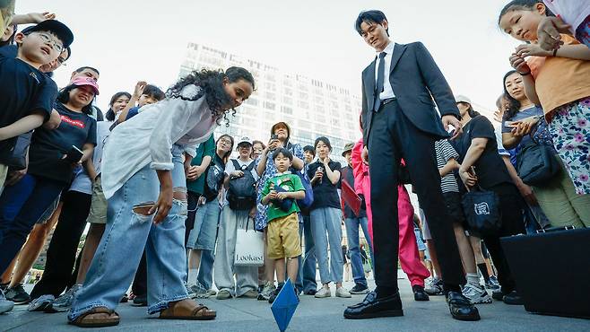29일 서울 종로구 광화문광장에서 '2025 K콘텐츠 서울여행주간: 소울스팟을 찾아라' 행사의 일환으로 마련된 넷플릭스 오징어 게임 체험존에서 외국인 관광객이 딱지치기를 하고 있다.