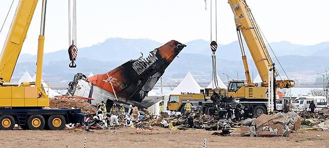 지난해 12월29일 태국 방콕에서 오던 제주항공 여객기가 무안공항에 착륙하던 중 추락해 구조대원들이 사고 지점 비행기 동체 안에서 찾은 승객 시신을 활주로에 임시로 마련된 대기장소로 옮기고 있다.