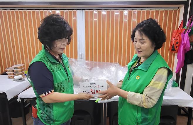 김인숙 회장(왼쪽)이 직접 만든 물김치를 회원에게 전달하고 있다. /새마을부녀회 제공