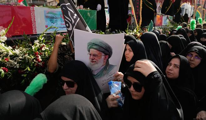28일 이란 수도 테헤란에서 최근 이스라엘의 공습으로 숨진 호세인 살라미 이란 혁명수비대 총사령관, 모하마드 바게리 군 참모총장 등의 장례식이 열렸다. 장례식에 참석한 시민들이 이란 최고지도자 알리 하메네이의 사진을 들고 행진하고 있다. 테헤란=AP 뉴시스