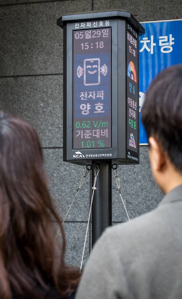 시민들이 지난달 29일 서울 금천구 SK브로드밴드 가산데이터센터 입구에 세워진 전자파 신호등을 살펴보고 있다. 전자파 신호등은 한국방송통신전파진흥원(KCA)이 자체 개발한 사물인터넷(IoT) 기반 서비스로, 실시간 전자파 측정 정보를 기지국 인근 주민들에게 3색의 신호등으로 알기 쉽게 제공한다. 박동욱기자 fufus@